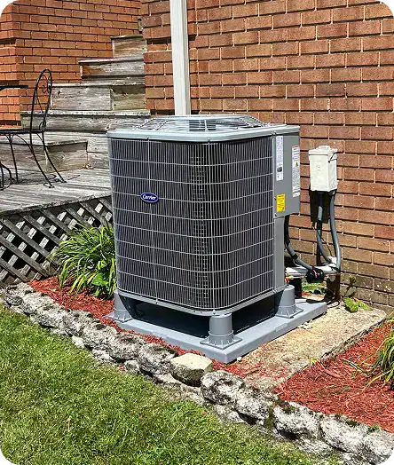 A professional installation of a Carrier air conditioning unit by the Childers team, mounted on a concrete pad beside a brick home.