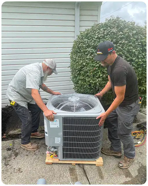 Two members of the Childers team carefully place a new outdoor air conditioning unit onto a concrete pad.