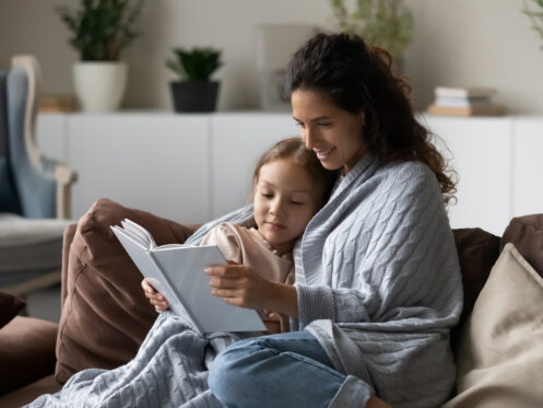 Mother and daughter curling up together reading a book